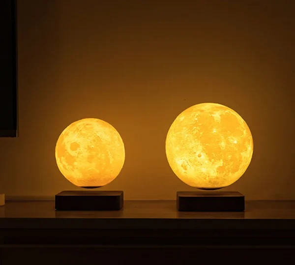 Two illuminated spherical lamps designed to resemble the moon, sitting on square bases against a dark background. Two illuminated spherical lamps designed to resemble the moon, sitting on square bases against a dark background.