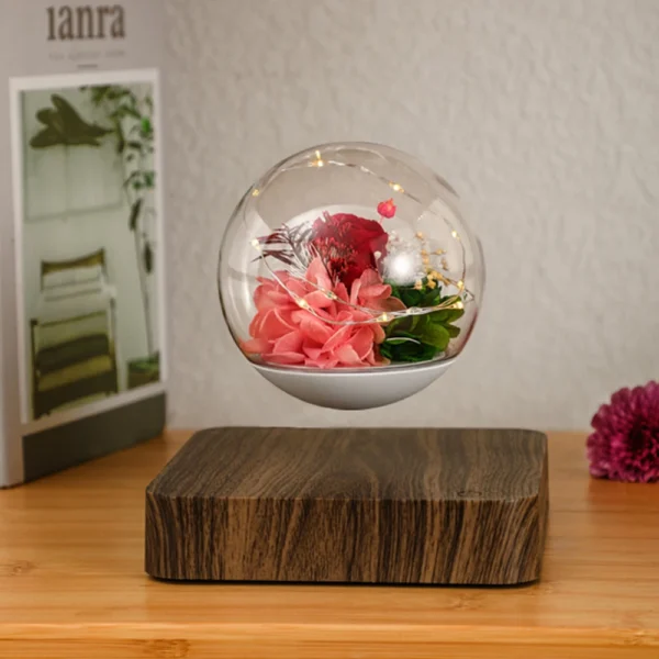 Magnetic Levitating Preserved Flower Rotation Flower Lamp Creative Floating LED Night Light For Home Desk Office Decoration 1 A glass orb with pink and red flowers floats above a wooden base on a table.
